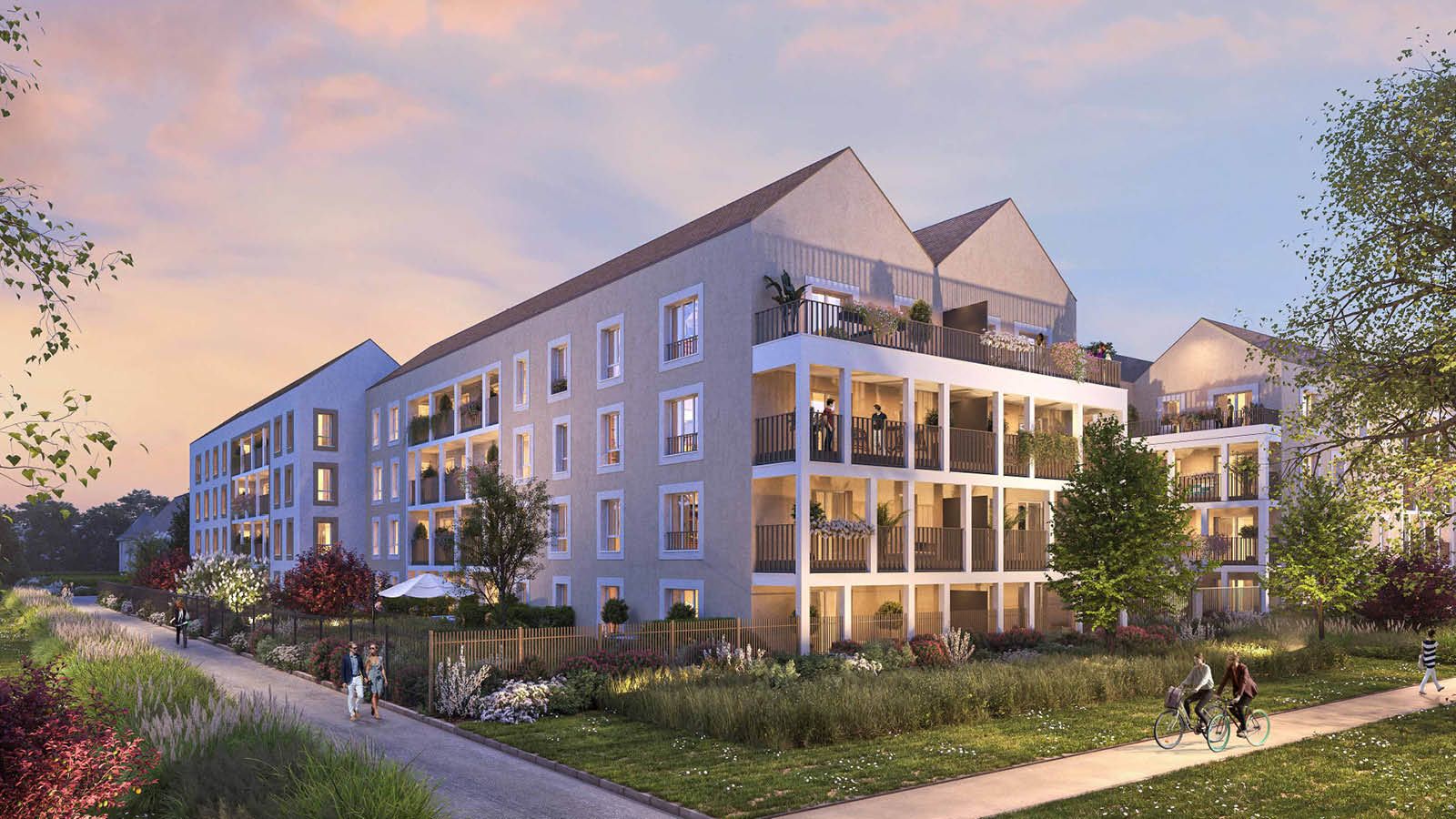 Immeuble résidentiel moderne au coucher de soleil, avec façades colorées et espaces verts environnants.