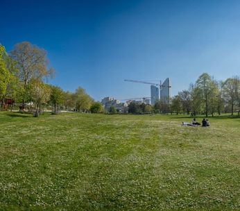 Parc verdoyant avec skyline urbaine en arrière-plan par jour ensoleillé.