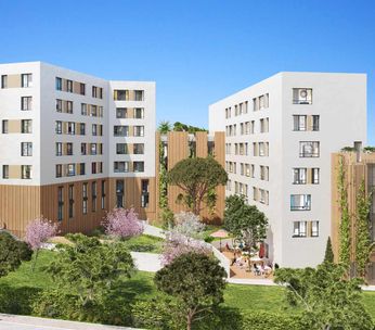 Immeubles résidentiels modernes aux façades colorées entourés d'espaces verts sous un ciel bleu.