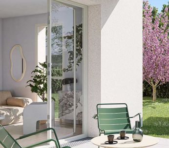 Maison moderne avec terrasse ouverte, salon lumineux et jardin paysagé sous un ciel dégagé.