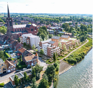 Vue aérienne d'une ville riveraine avec église et rivière sinueuse sous ciel dégagé.