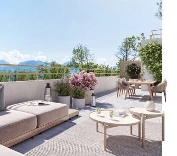 Terrasse moderne avec canapé gris, vue sur montagnes et fleurs roses en arrière-plan.