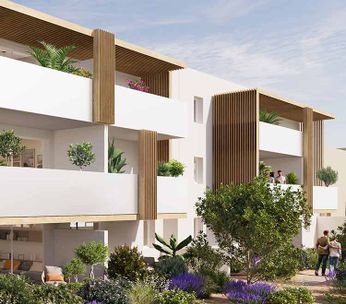 Immeuble résidentiel moderne avec façade blanche, entouré de palmiers et verdure, sous ciel dégagé.