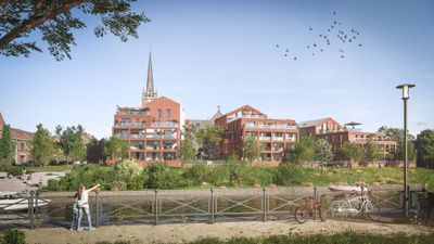 Paysage urbain avec bâtiments résidentiels rouges, église au fond, parc verdoyant au premier plan et ciel dégagé.