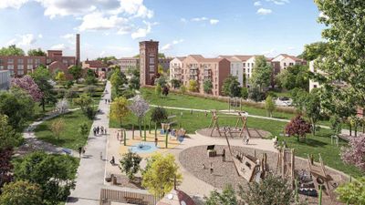 Parc urbain avec immeubles résidentiels rouges en arrière-plan sous un ciel dégagé.