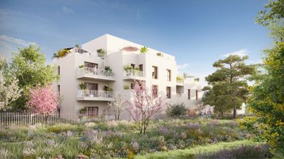 Immeuble résidentiel moderne blanc entouré de végétation et fleurs roses sous ciel bleu.