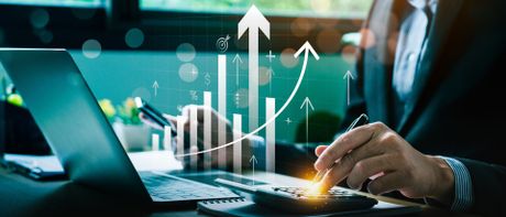 Homme analysant des graphiques financiers en hausse sur un ordinateur portable avec hologramme de données.