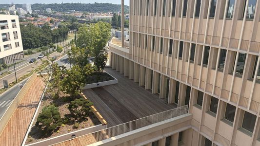 Vue aérienne d'une cour intérieure urbaine avec arbres et bâtiments modernes en pierre beige.