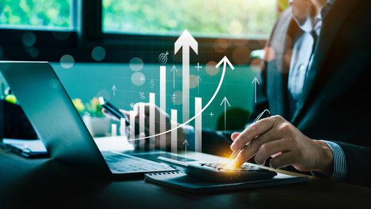 Homme analysant des graphiques financiers en hausse sur un ordinateur portable avec hologramme de données.