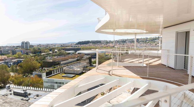 Terrasse moderne surplombant une vue panoramique urbaine et verdoyante.