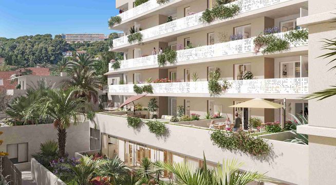 Immeuble résidentiel moderne avec balcons terrasses et végétation, surplombant un paysage boisé sous ciel bleu.