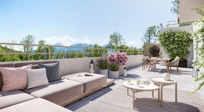 Terrasse ensoleillée avec mobilier gris, coussins roses et vue sur les montagnes en arrière-plan.
