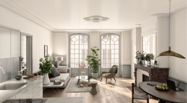 Salon lumineux avec mobilier moderne, plantes vertes et grandes fenêtres donnant sur l'extérieur.