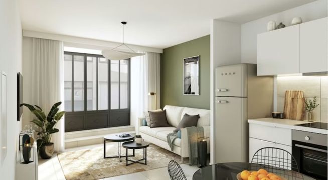 Studio moderne avec cuisine ouverte, canapé beige et grandes fenêtres donnant sur balcon.