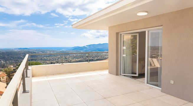 Terrasse spacieuse avec vue panoramique sur les montagnes et vallée ensoleillées.
