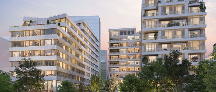 Immeubles résidentiels modernes aux façades claires, entourés de verdure, sous un ciel nuageux.