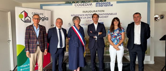 Groupe de neuf personnes en tenue formelle posant ensemble dans un bureau moderne.